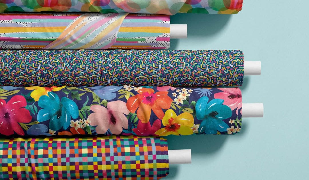 Rolls of colorful fabric with various patterns on a light blue background
