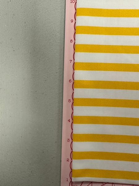 a yellow and white striped wall hanging next to a ruler