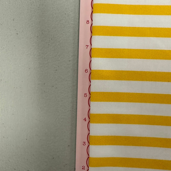 a yellow and white striped wall hanging next to a ruler