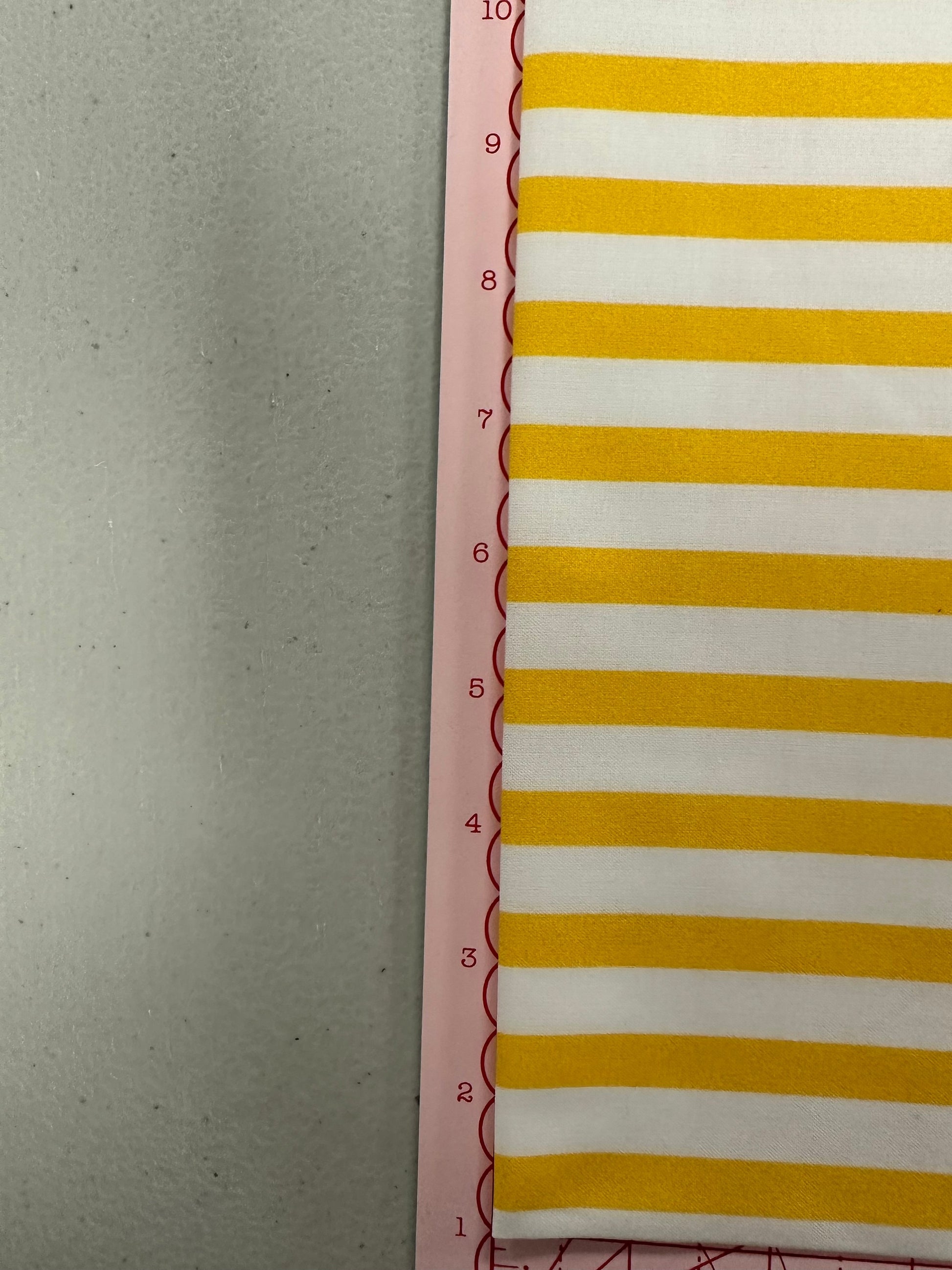 a yellow and white striped wall hanging next to a ruler