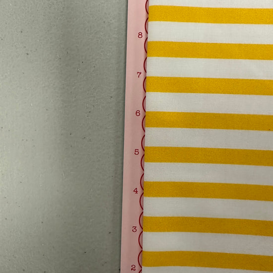 a yellow and white striped wall hanging next to a ruler