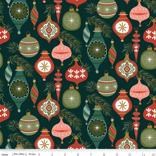 Image of Christmas Is in Town Ornaments Forest by Riley Blake Designs. Features Christmas ornaments on a dark green background with sprigs of pine needles. 
Cute Little Fabric Shop