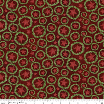 Image of the Up on the Housetop Star Wreaths Cranberry quilting cotton fabric by Riley Blake Designs. Features stars inside of a pine needle wreath on an dark red background. 
Cute Little Fabric Shop