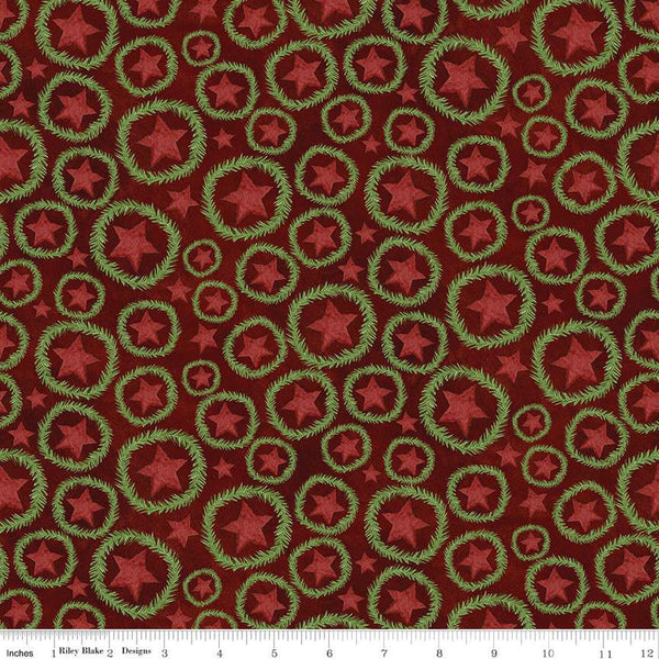 Image of the Up on the Housetop Star Wreaths Cranberry quilting cotton fabric by Riley Blake Designs. Features stars inside of a pine needle wreath on an dark red background. 
Cute Little Fabric Shop