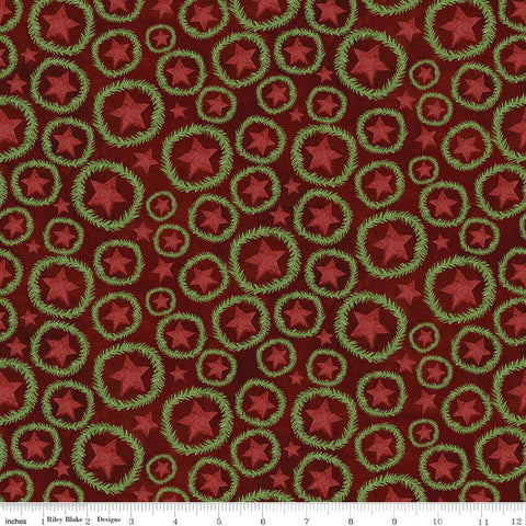 Image of the Up on the Housetop Star Wreaths Cranberry quilting cotton fabric by Riley Blake Designs. Features stars inside of a pine needle wreath on an dark red background. 
Cute Little Fabric Shop