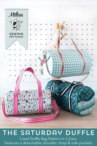 Image of the Melissa Mortenson Saturday Duffle Bag Pattern. Features a round, lined zippered duffle bag with an optional exterior pocket and a detachable shoulder strap. 
Cute Little Fabric Shop