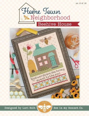 Image of the Home Town Neighbor Beehive House cross stitch pattern  by Lori Holt for Riley Blake Designs. Features a house and a beehive with a flower and bee on a cross stitch pattern. 
Cute Little Fabric Shop