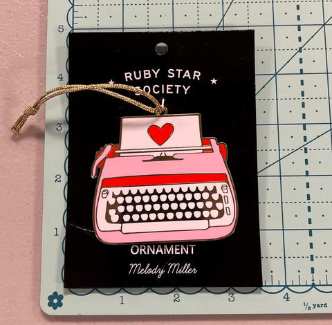 Image of the typewriter ornament for Ruby Star for Moda. Features a pink typewriter with a red heart. 
Cute Little Fabric Shop