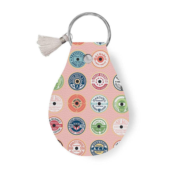 Image of the Leather Circle Key Chain Sew Much Fun by Ashley Collett for Riley Blake Designs. Features a bobbin design on a full grain leather keychain with tassel. 
Cute Little Fabric Shop