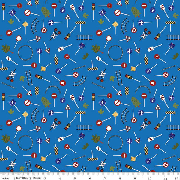 Image of the It Takes a Village Traffic Signs Blue quilting cotton fabric by Jennifer Long for Riley Blake Designs. Features street signs, trees, train tracks, and more on a blue background. 
Cute Little Fabric Shop