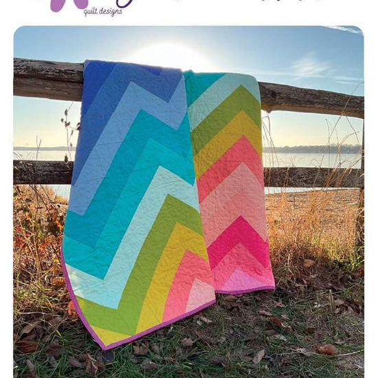 Image of the Kenzie Quilt Pattern by Purple Daisy Quilt Designs for Riley Blake Designs. Features half square triangles that create a rainbow of elongated chevron stripes. 
Cute Little Fabric Shop