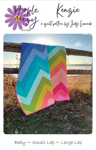 Image of the Kenzie Quilt Pattern by Purple Daisy Quilt Designs for Riley Blake Designs. Features half square triangles that create a rainbow of elongated chevron stripes. 
Cute Little Fabric Shop