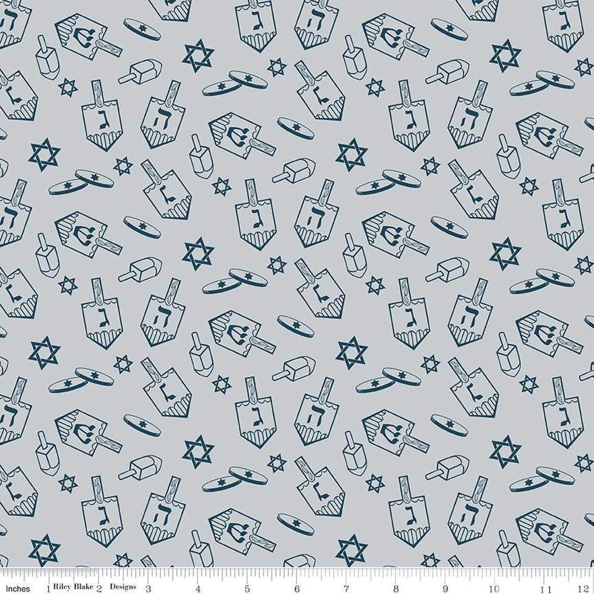 Image of the 8 Nights, 8 Lights Dreidel Toss Silver quilting cotton fabric by Riley Blake Designs. Features dreidels on a gray background. Cute Little Fabric Shop