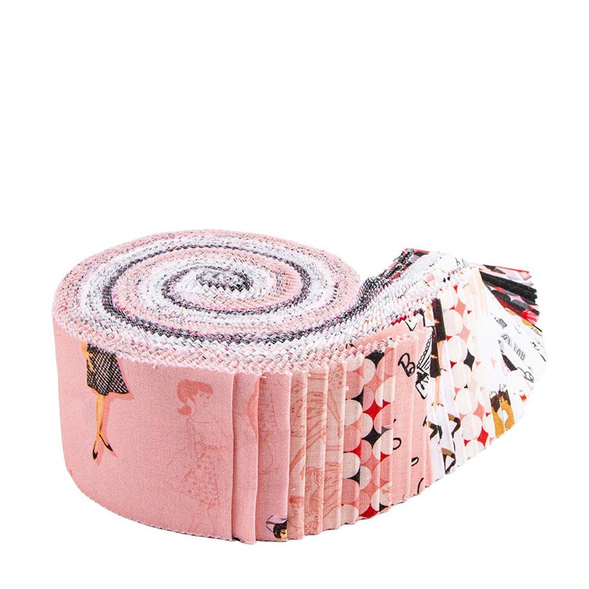 A roll of fabric with various patterns and designs, including a pink fabric with a woman's silhouette and other decorative elements.