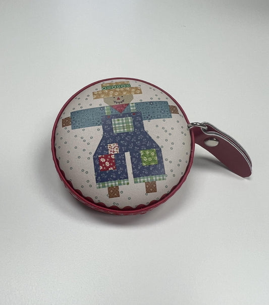 A round, colorful pouch or coin purse with a patchwork design depicting a scarecrow or scarecrow-like figure.