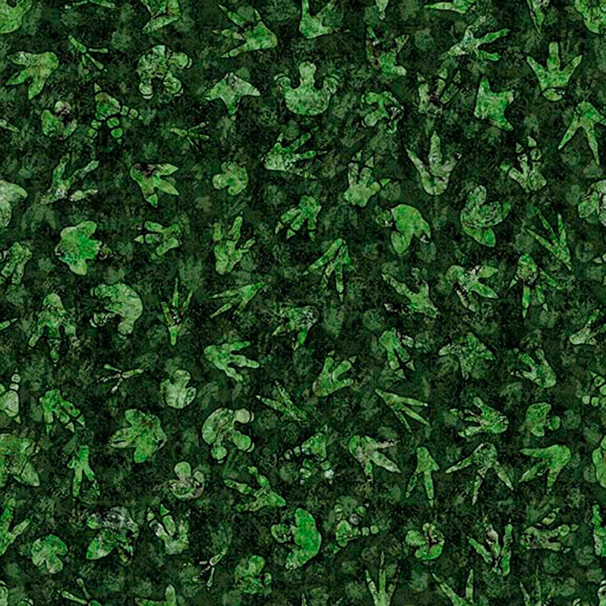 Image of Savage Kingdom Dino Tracks Forest quilting cotton fabric by Dan Morris for QT Fabrics. Features dinosaur footprints on a green background. Cute Little Fabric Shop.