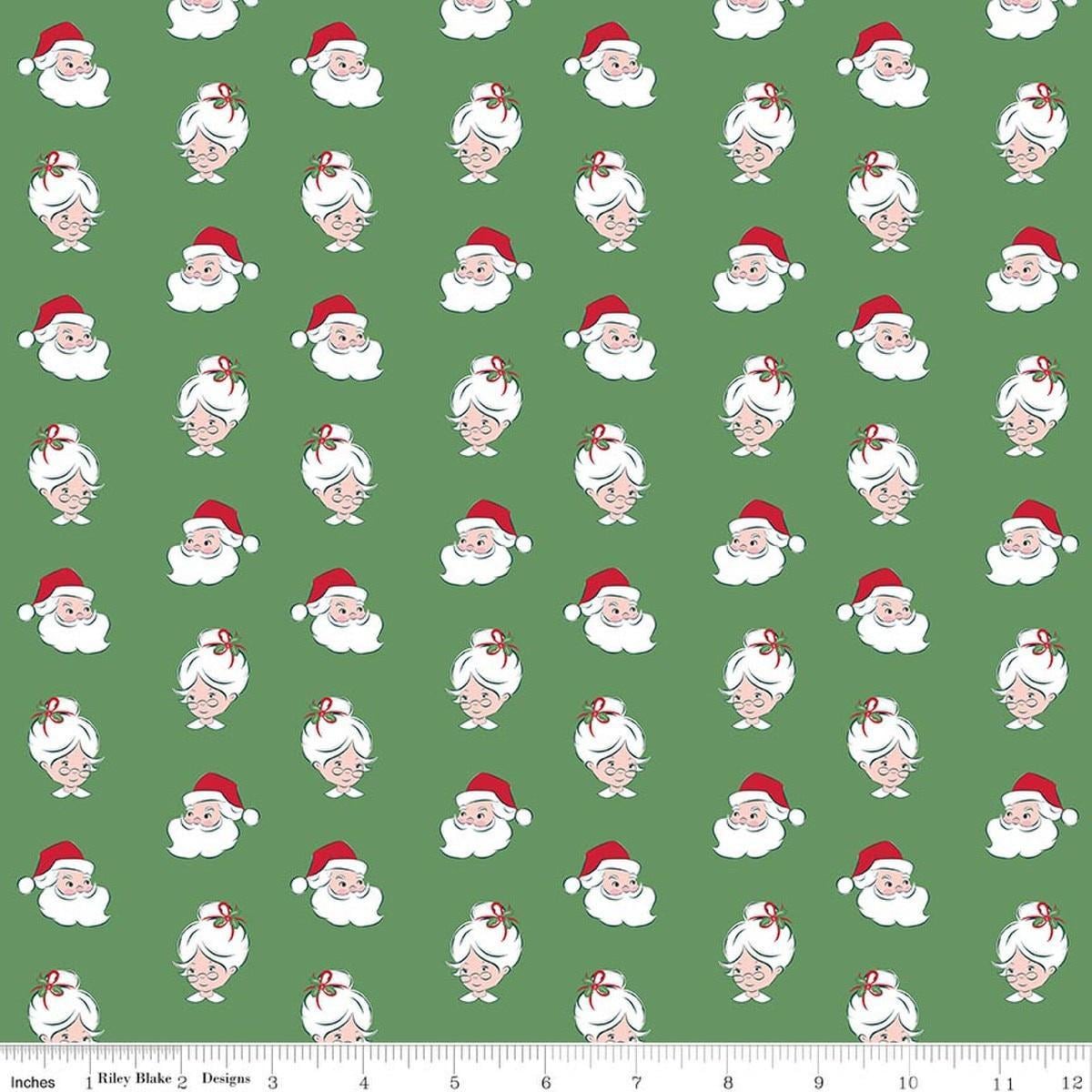 Image of Claus & Co. Santa Heads Green quilting cotton fabric by Melissa Mortenson for Riley Blake Designs. Features santa heads on a green background. Cute Little Fabric Shop.