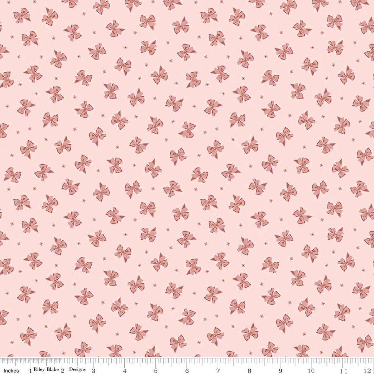 Image of Rosewood Petticoat Pink quilting cotton fabric by Jessica Chertkow for Riley Blake Designs. Features bows on a pink background. Cute Little Fabric Shop.