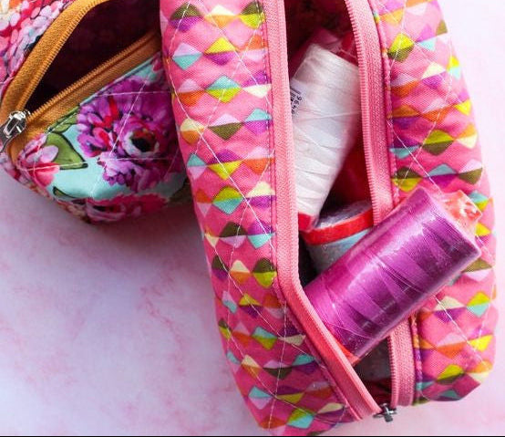 Colorful makeup bags with items on a pink background